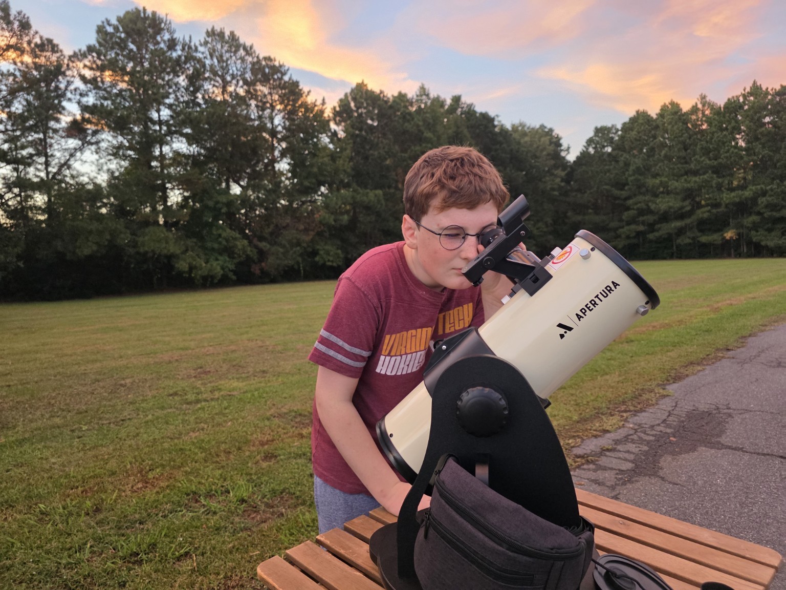 A young observer using the Apertura Library Telescope at sunset