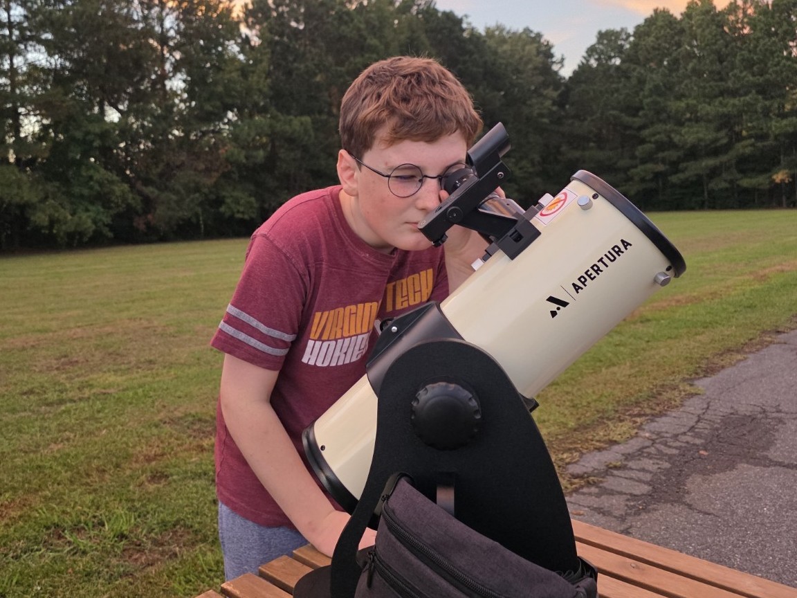 A young observer using the Apertura Library Telescope at sunset